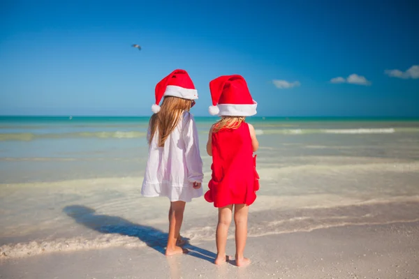 Little cute girls in Christmas hats on the exotic beach — Stock Photo, Image